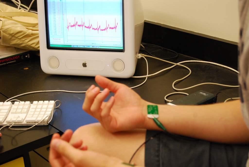 Wrists of student hooked up with sensors leading to an ECG and screen readout.